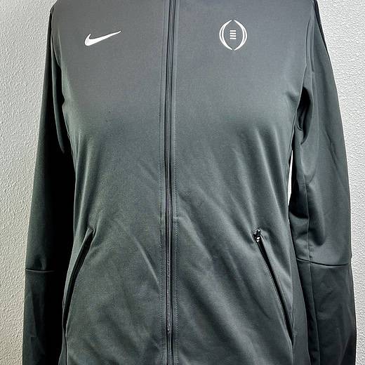 A front view of a Nike full-zip jacket in grey, featuring the Nike logo on the right chest and a College Football Playoff emblem on the left. The jacket has a high collar, zippered pockets, and is displayed on a mannequin against a neutral background.