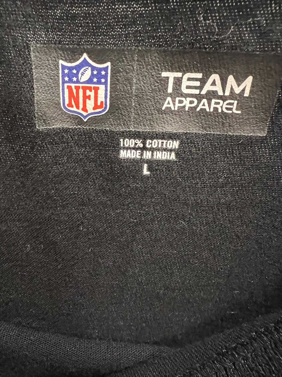 Tag close-up confirming NFL Team Apparel branding and 100% cotton material, made in India, labeled size L (Large).
