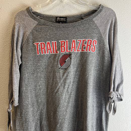 Full view of the stylish Portland Trail Blazers long-sleeve top, featuring a wide neckline, cold shoulder design with tied sleeves, and the team's iconic logo.