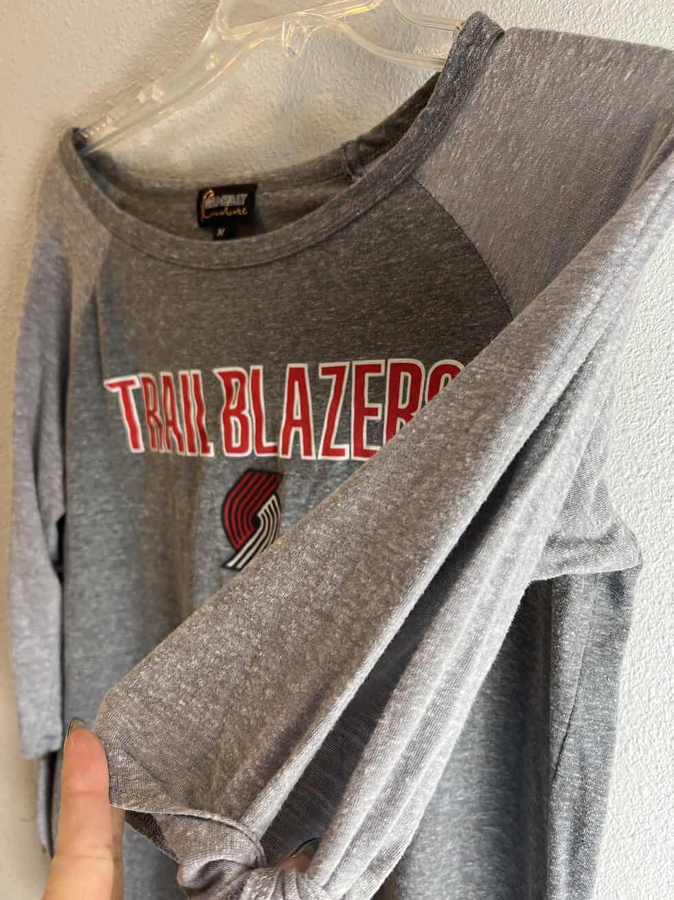 Fashionable gray Portland Trail Blazers long-sleeve gameday top with cold shoulder sleeves tied at the cuffs and team branding across the chest.