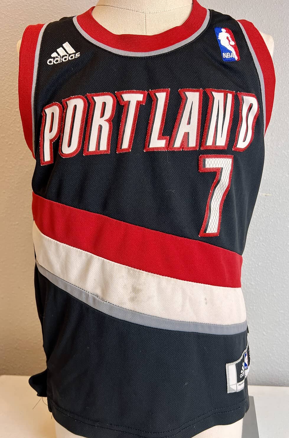 Adidas Portland Trail Blazers NBA jersey in black with red and white stripes, featuring 'PORTLAND' and the number '7' on the front,