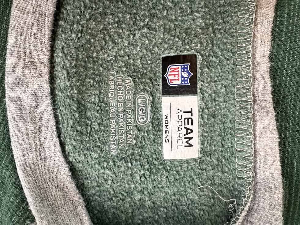 Tag on the inside of a New York Jets sweatshirt showing the NFL Team Apparel logo, size 'Women's', and 'Made in Pakistan' label.