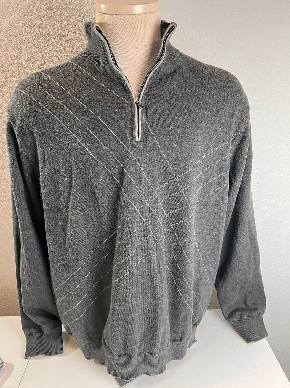 Charcoal grey quarter-zip sweater with a subtle diagonal argyle pattern and ribbed high collar, offering a sophisticated yet comfortable look.
