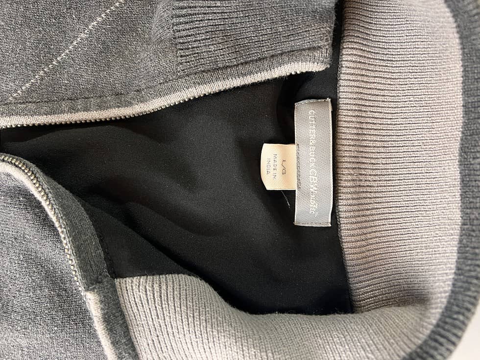 Inner label of a charcoal grey sweater indicating the brand Cutter & Buck, size Men's Large, and 'Made in India' tag.