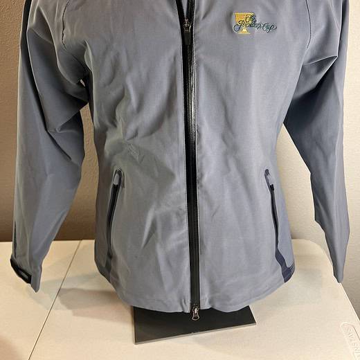 Light grey Sun Mountain rain jacket with a full zipper front, zippered pockets, and the 2013 Presidents Cup logo embroidered on the chest.