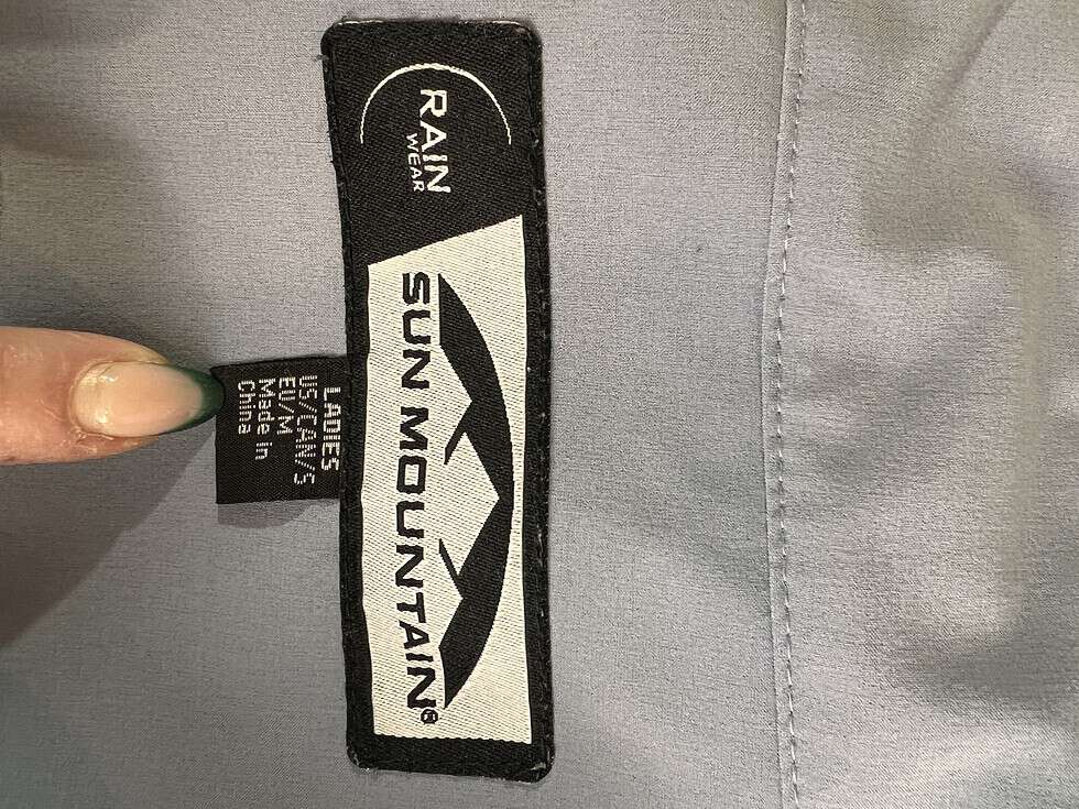 Tag inside the Sun Mountain rain jacket indicating the brand, size as Medium, and the text 'RAINwear', with care instructions and 'Made in China' label.