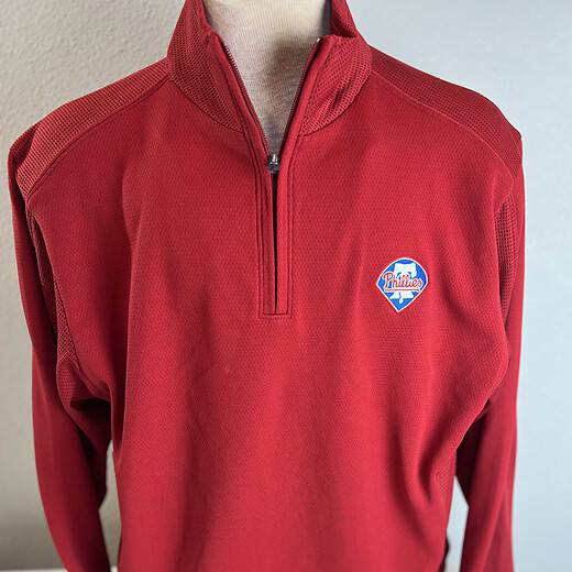 Bright red Philadelphia Phillies quarter-zip pullover with contrasting textured panels and the team's bell logo on the upper left chest.