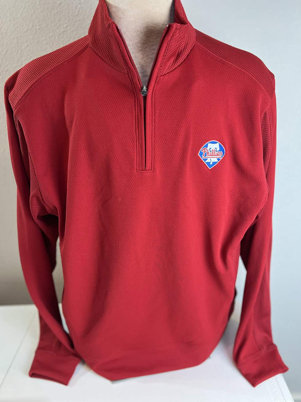 Bright red Philadelphia Phillies quarter-zip pullover with contrasting textured panels and the team's bell logo on the upper left chest.