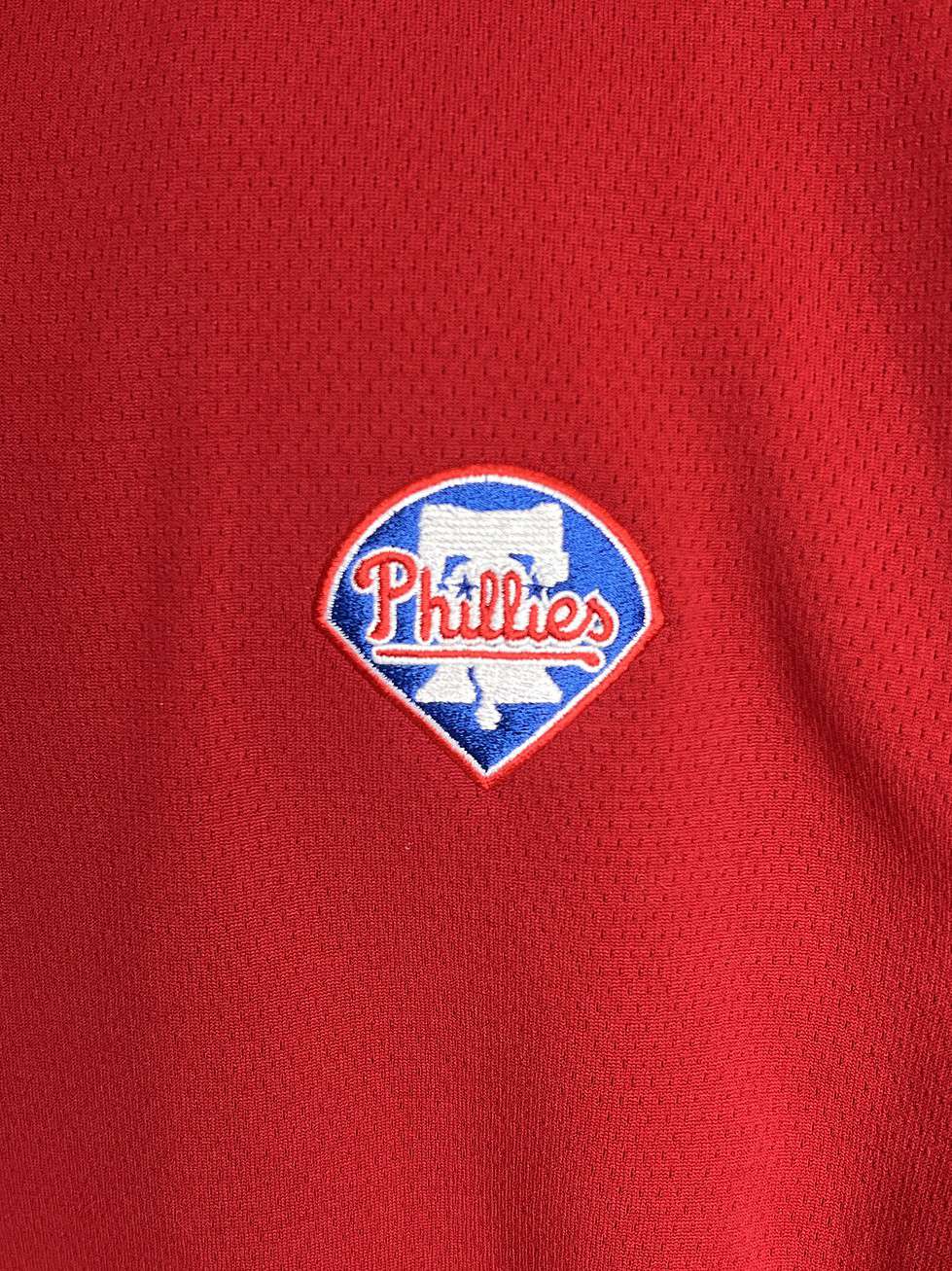 Close-up of the Philadelphia Phillies logo on a red quarter-zip pullover, showcasing the team's iconic blue and white "bell" emblem.