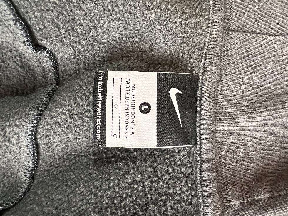 Tag inside a grey Nike hoodie showing the Nike logo and the URL 'nikebetterworld.com', with 'FABRIQUÉ EN INDONÉSIE' indicating it was made in Indonesia.