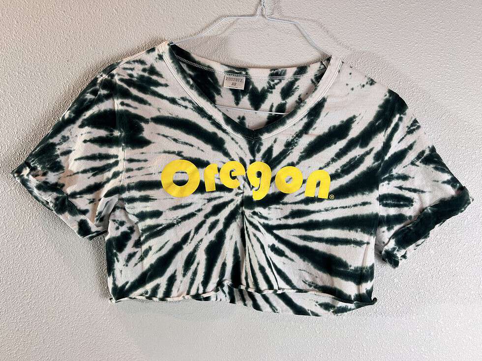 Stylish cropped t-shirt with a black and white tie-dye design, featuring bold yellow 'Oregon' lettering across the chest.