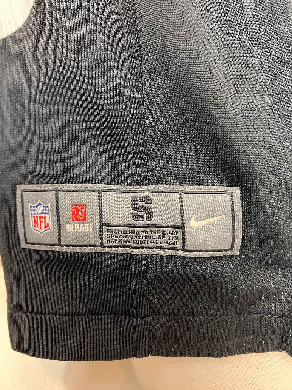 Tag on the bottom of the Steelers #26 jersey displaying the Nike logo and NFL branding, indicating size small, with 'Engineered to the exact specifications of the National Football League'.