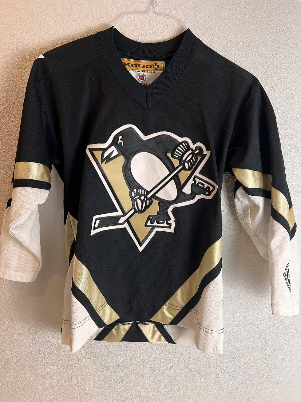 Classic Pittsburgh Penguins youth hockey jersey in black with white and gold accents, featuring the team's logo on the front and a V-neck design