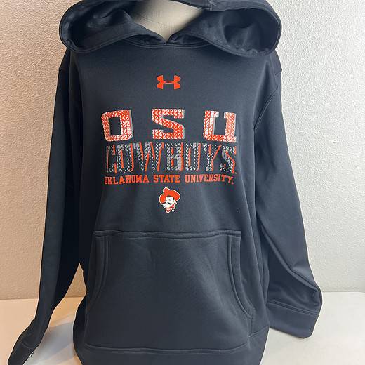 Youth-sized Under Armour hoodie in black, featuring 'OSU COWBOYS' lettering and Oklahoma State University mascot logo in orange, with a front pouch pocket.