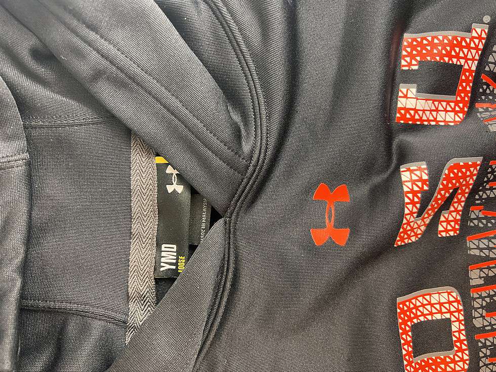 Close-up of the Under Armour logo on a black hoodie with the Oklahoma State University mascot logo and 'OSU COWBOYS' in orange, with a mesh-like fabric texture.