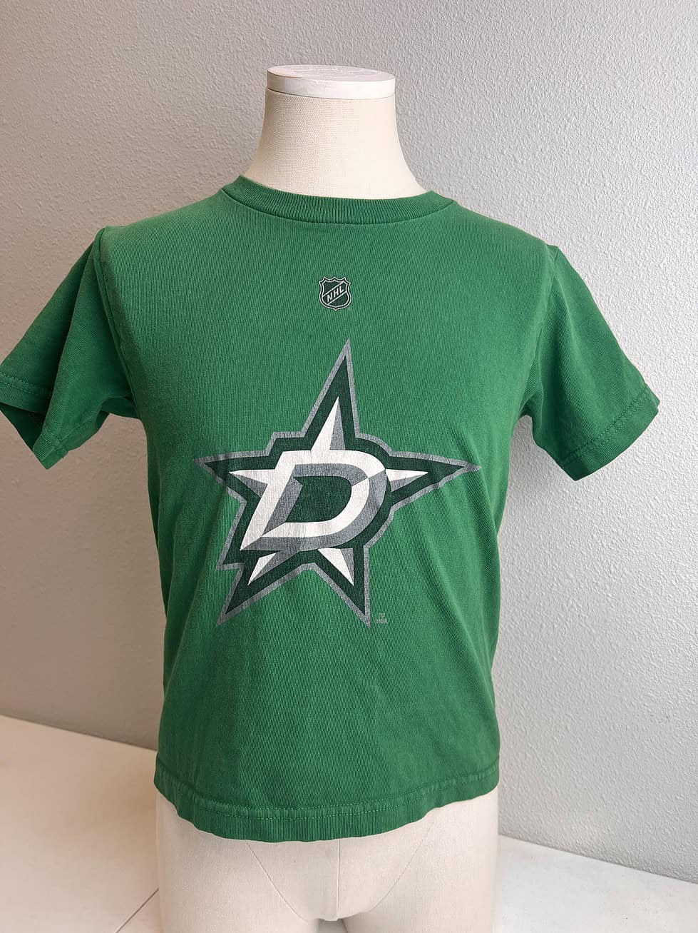 Front view of a child-sized Reebok t-shirt in victory green, displaying a prominent Dallas Stars logo, sized for a 4-year-old.