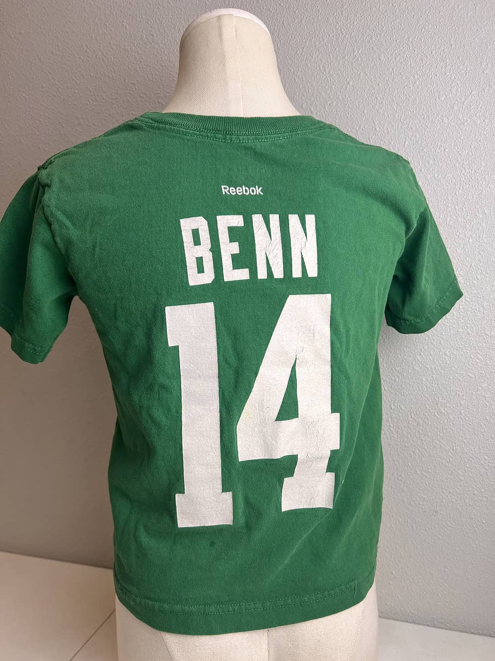 Back view of a child's green Reebok t-shirt with 'BENN 14' in large white letters, indicating Dallas Stars captain Jamie Benn's name and number.