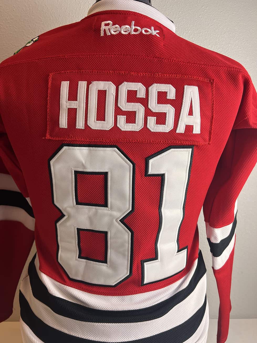Rear view of a Chicago Blackhawks jersey with ‘HOSSA’ and the number ‘81’ printed in bold white lettering.
