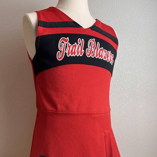 Full front view of the Trail Blazers red cheerleading dress with black accents and the team logo.