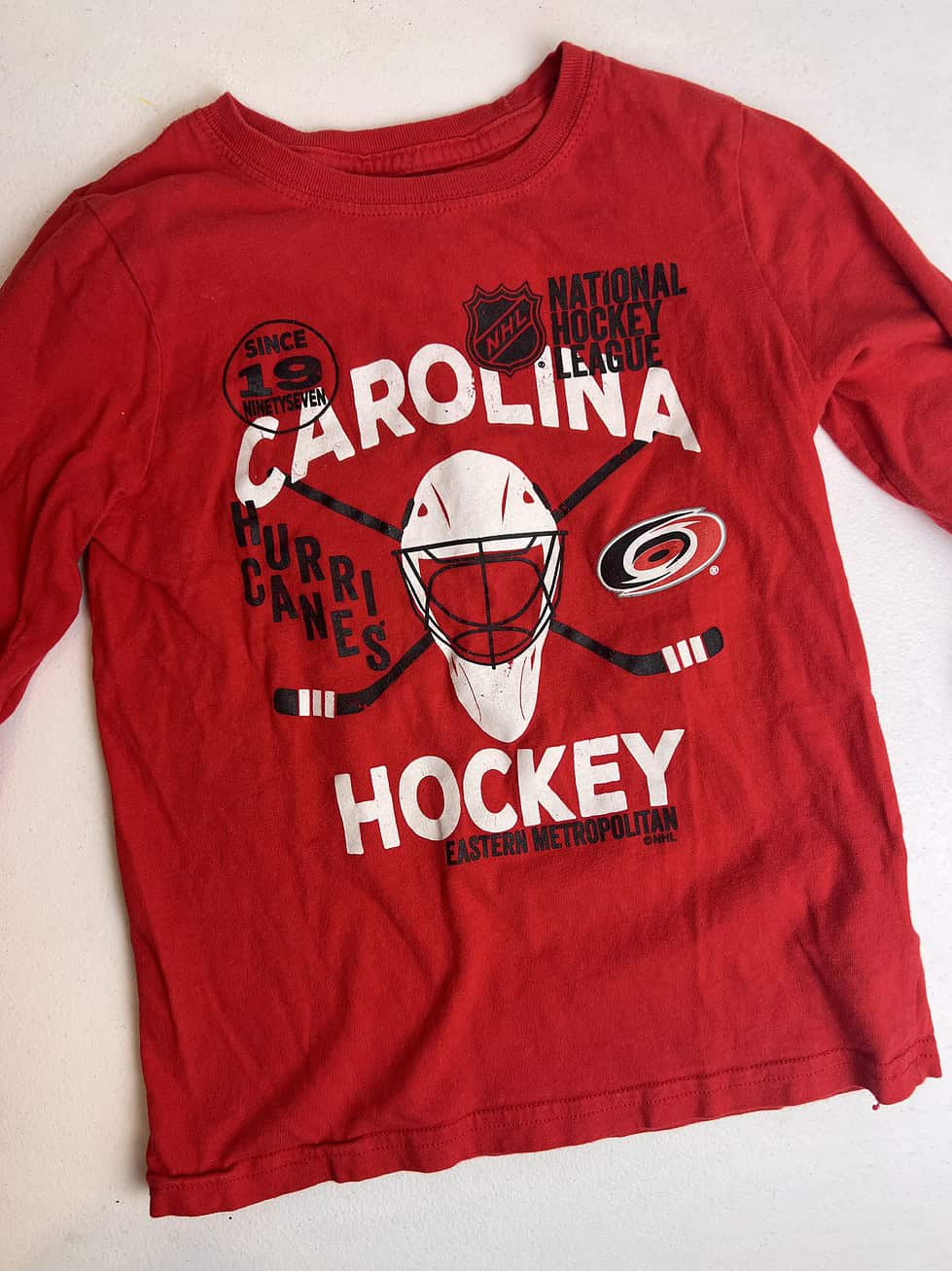 Youth size 7 Carolina Hurricanes long sleeve shirt in red featuring team graphics on the front.
