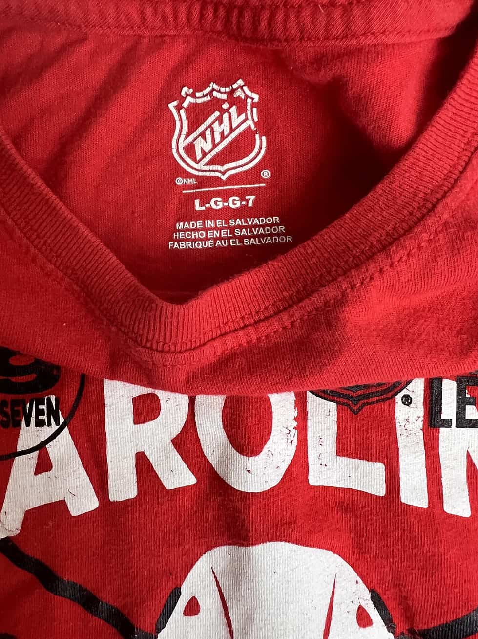 Close-up of the NHL logo on the neckline of a youth Carolina Hurricanes red long sleeve shirt.