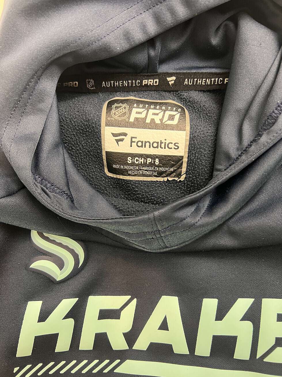 Tag inside a Seattle Kraken youth hoodie showing the Authentic Pro Fanatics brand and size 8 information.