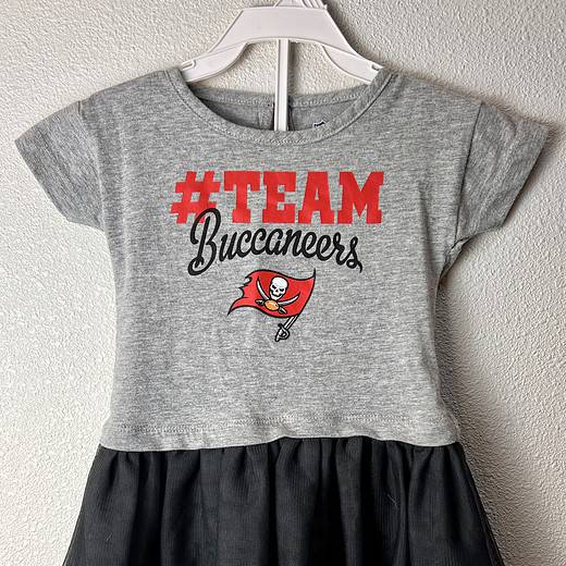 Gray toddler cheerleading dress with '#TEAM Buccaneers' print and the Buccaneers logo, featuring a black tulle skirt.