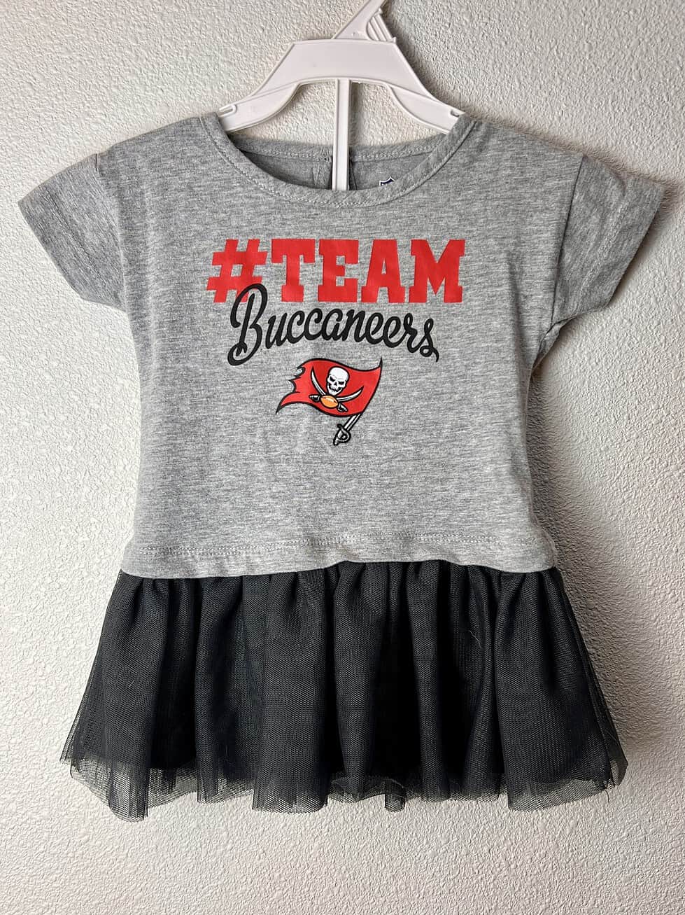 Gray toddler cheerleading dress with '#TEAM Buccaneers' print and the Buccaneers logo, featuring a black tulle skirt.