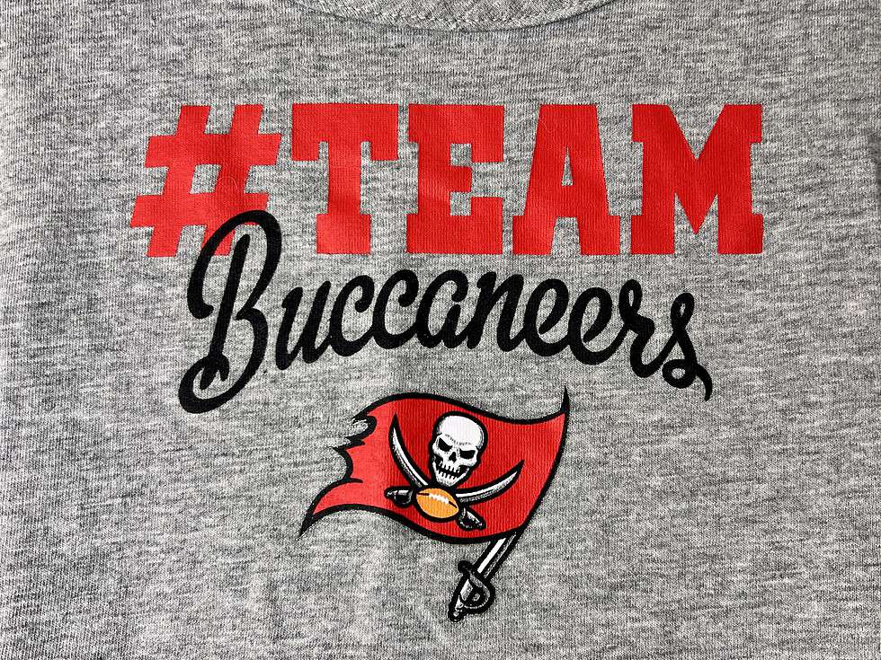 Close-up of the '#TEAM Buccaneers' print on the gray cheerleading dress, highlighting the team's logo with a red and black design.