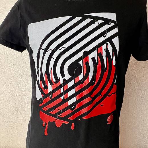 Full view of a Portland Trail Blazers youth T-shirt, showcasing the dripping logo design in team colors on a black background.