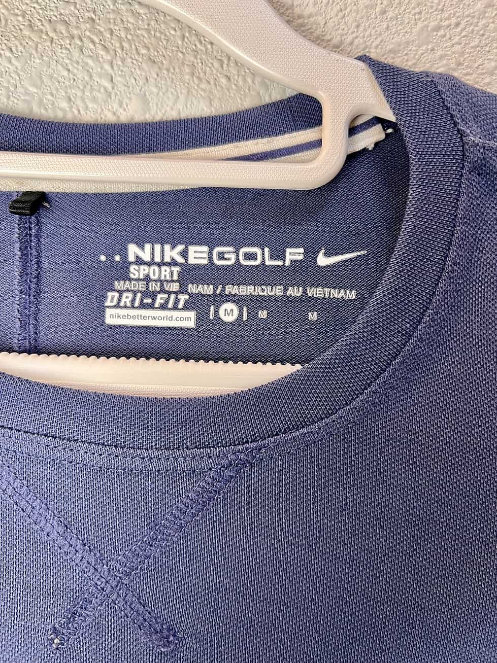 Close-up of the Nike Golf label inside a blue pullover, showing Dri-FIT technology and size medium.