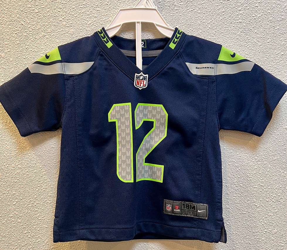 Front view of Seattle Seahawks toddler jersey in navy blue. The number 12 on front is in silver with neon green outline. NFL crest and jersey patch included.