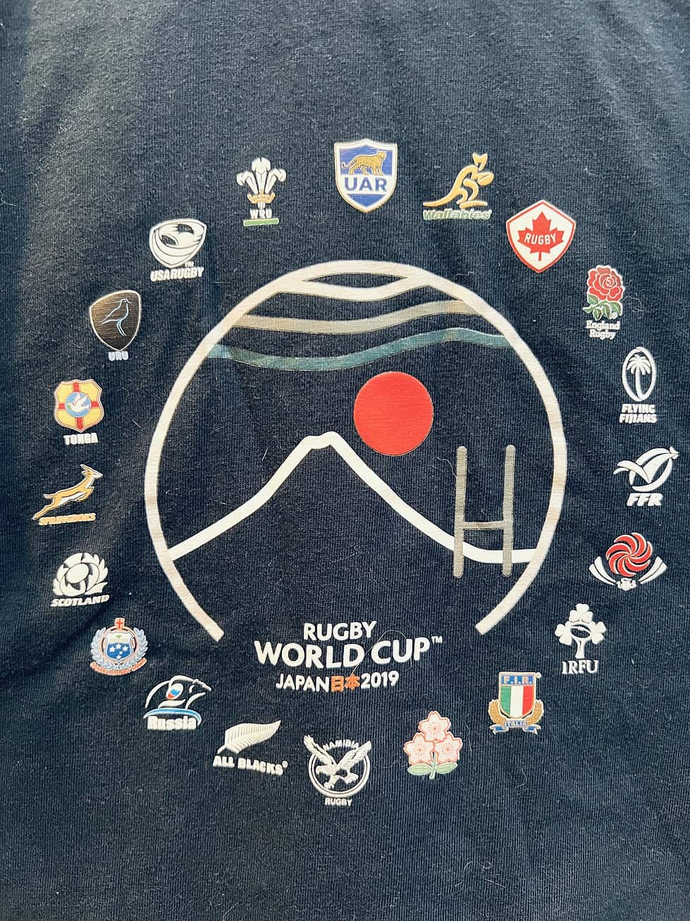Close-up of Rugby World Cup Japan 2019 logo and flags on black t-shirt.