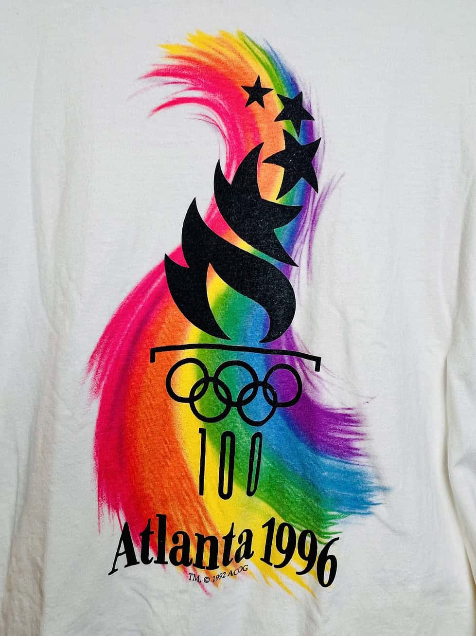 Close-up of colorful rainbow flame under the Atlanta 1996 Olympics logo on vintage white tee