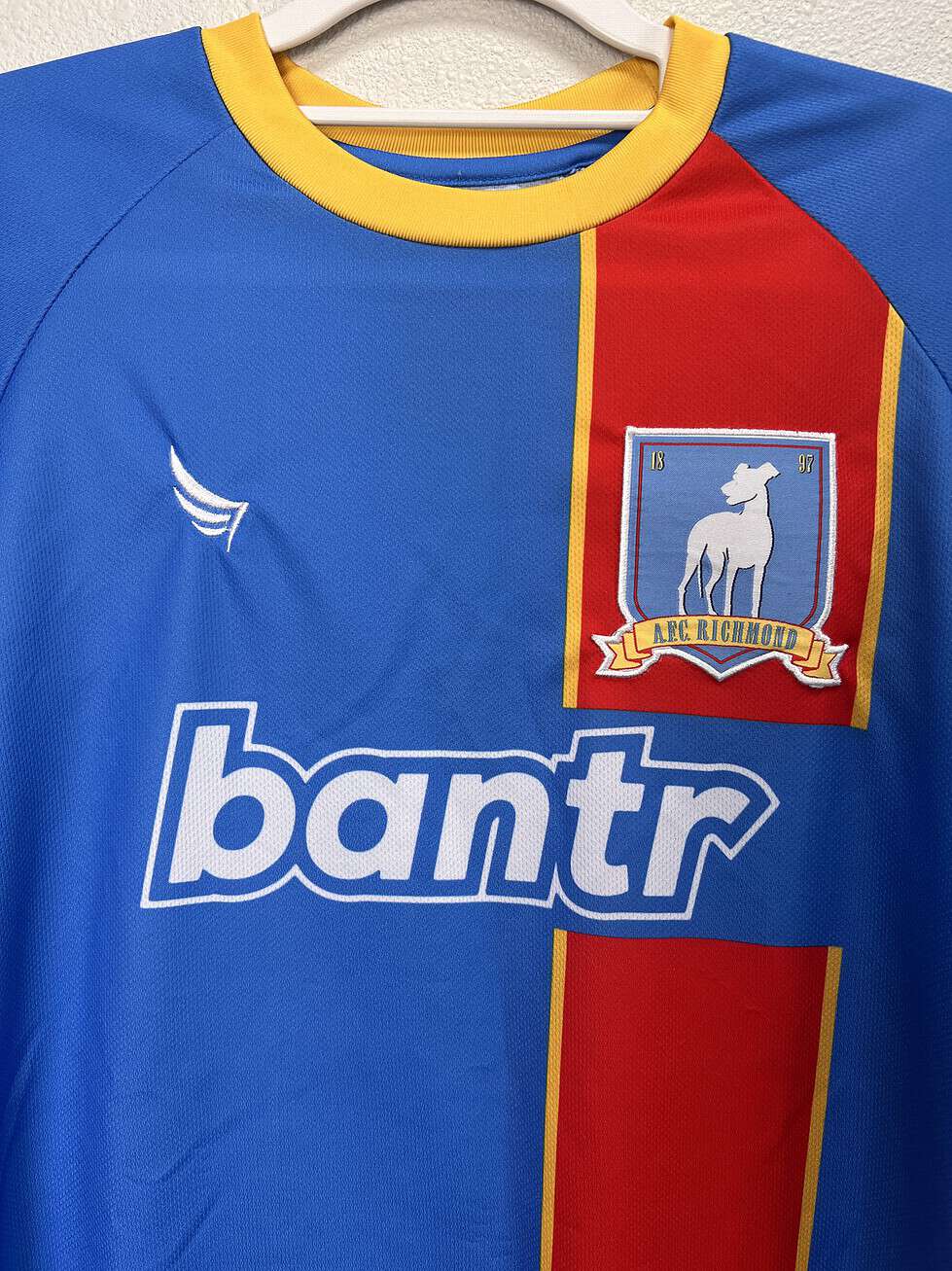 Close-up of the AFC Richmond crest and "bantr" logo on the Ted Lasso jersey.