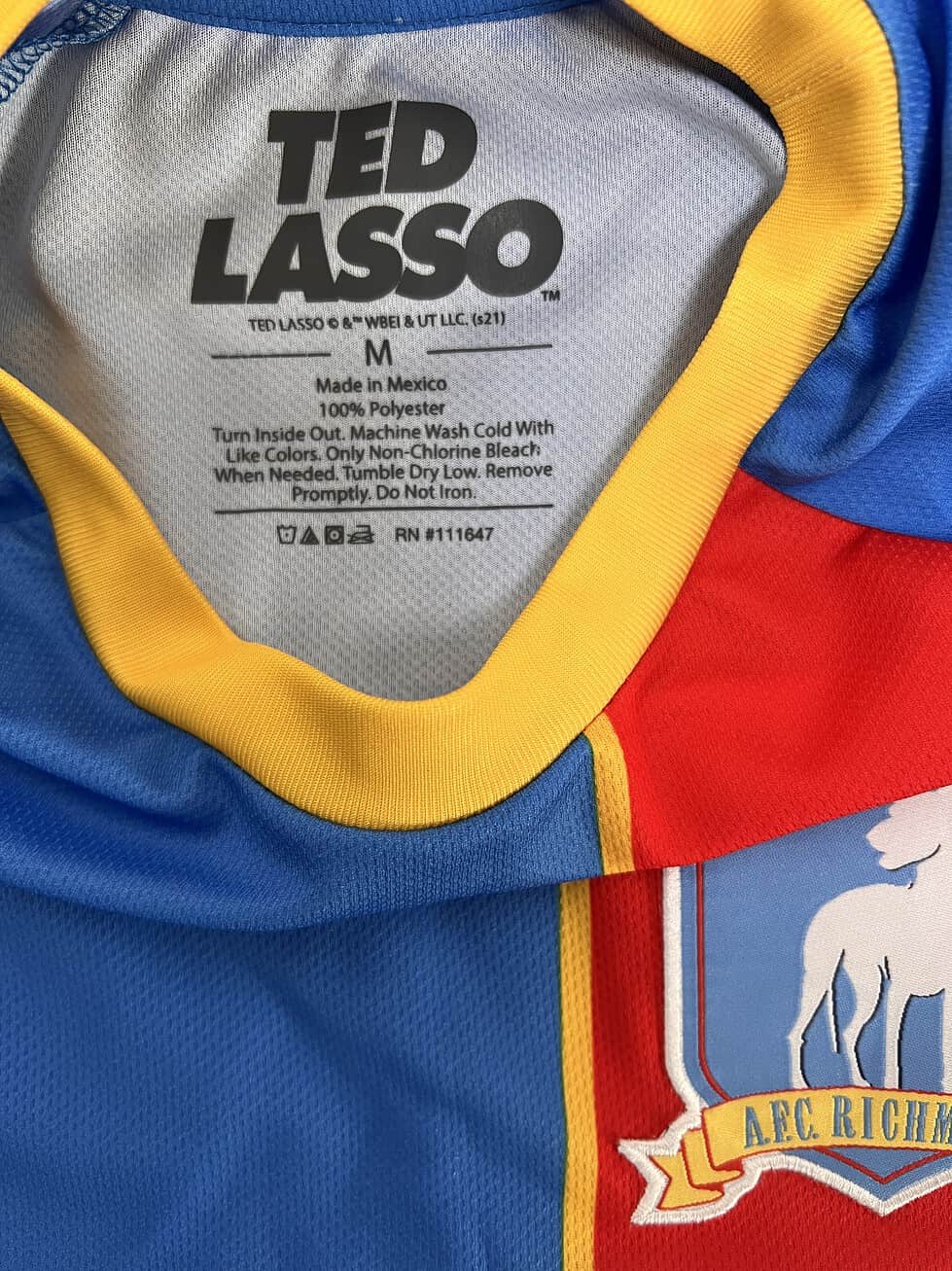 Inside view of the Ted Lasso tag on the AFC Richmond Jersey, made from 100% polyester, size Medium.