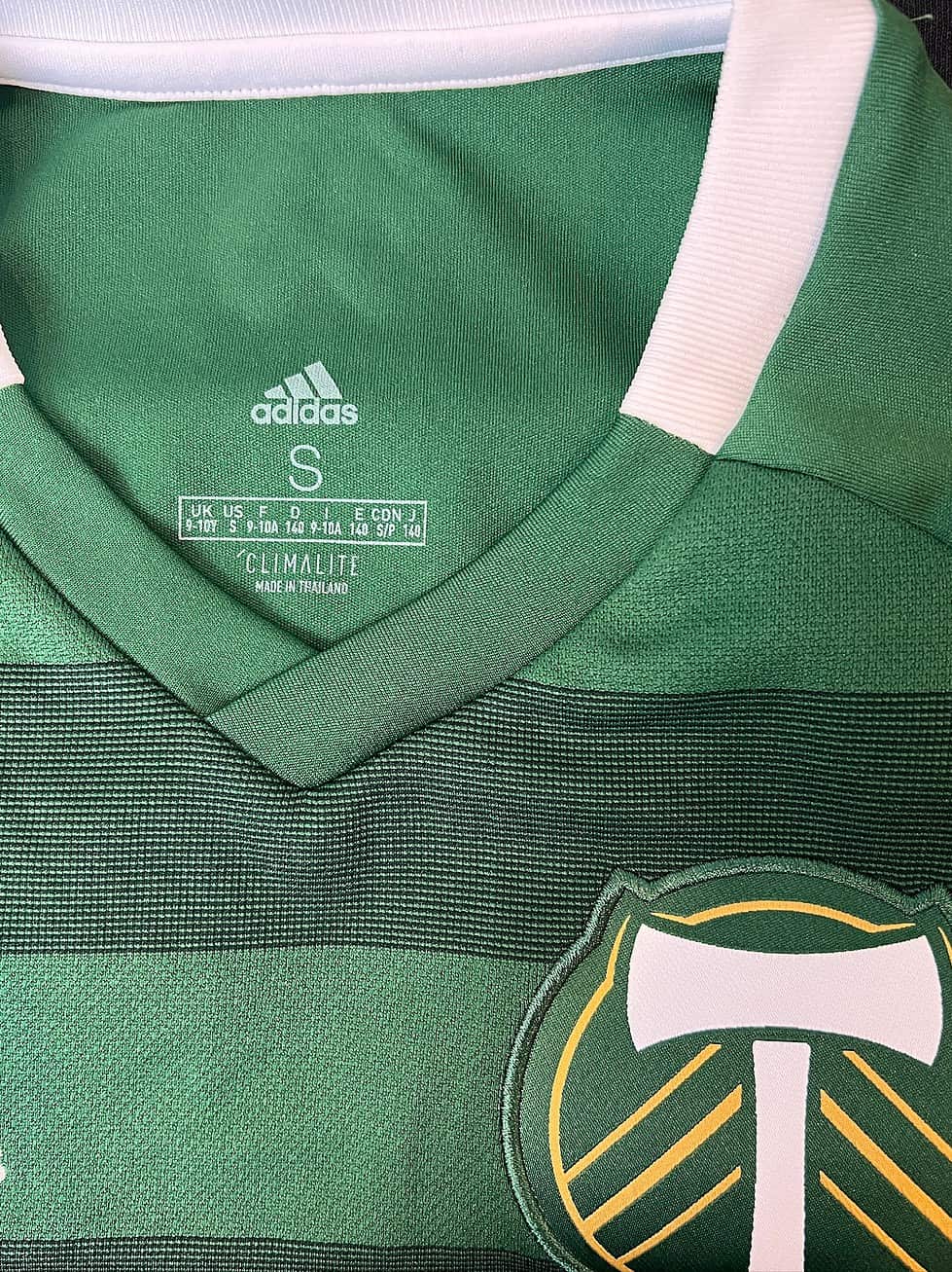 Size tag close-up of a Portland Timbers youth jersey, indicating youth small (S) with Adidas Climalite branding.