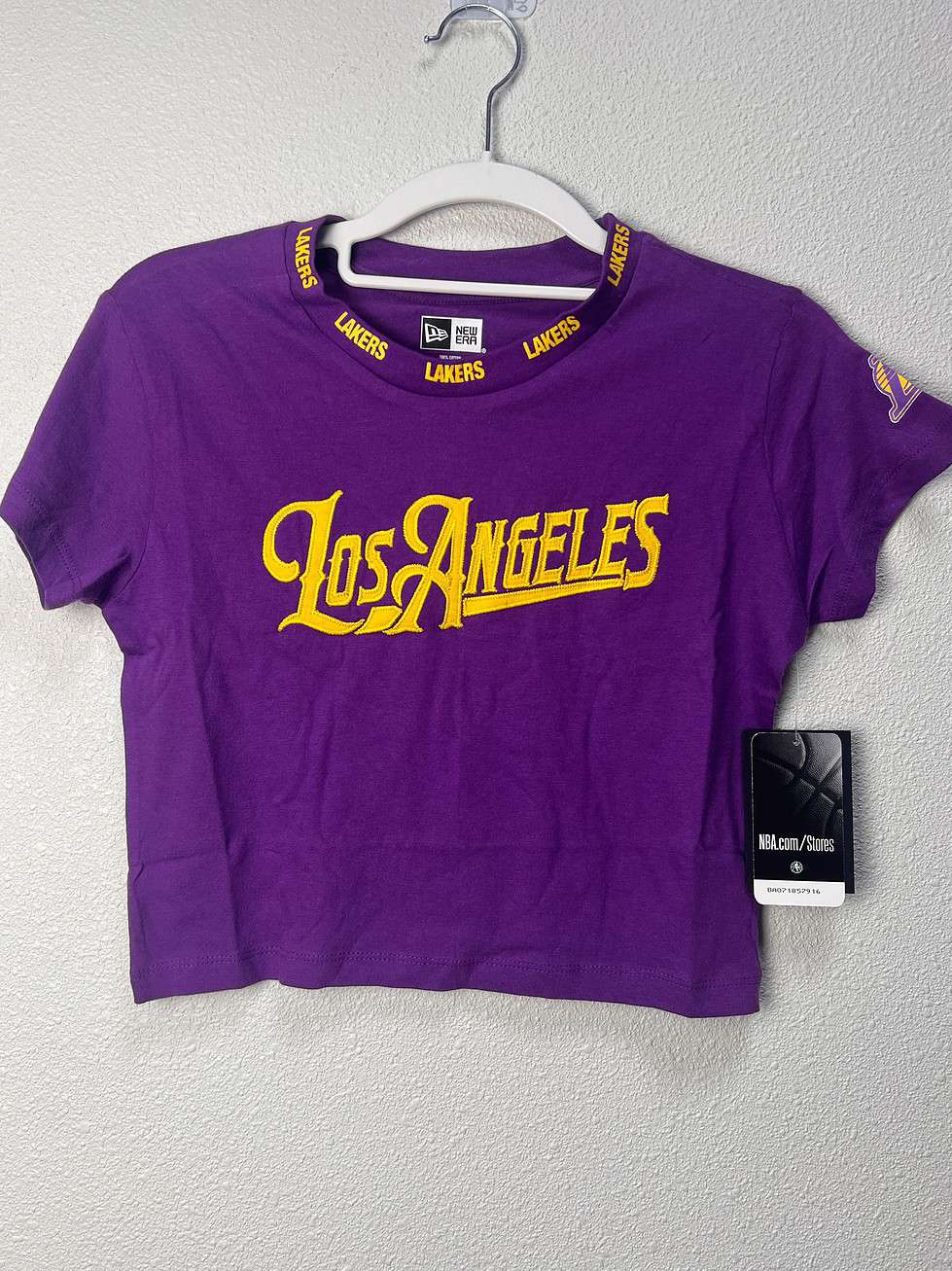 Front view of a purple Los Angeles Lakers women’s crop tee by New Era, size XS, featuring "Los Angeles" in gold lettering and Lakers branding on the collar.