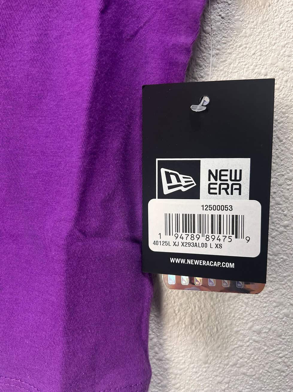Close-up of the NBA Store tag and New Era branding on a purple Los Angeles Lakers women’s crop tee.