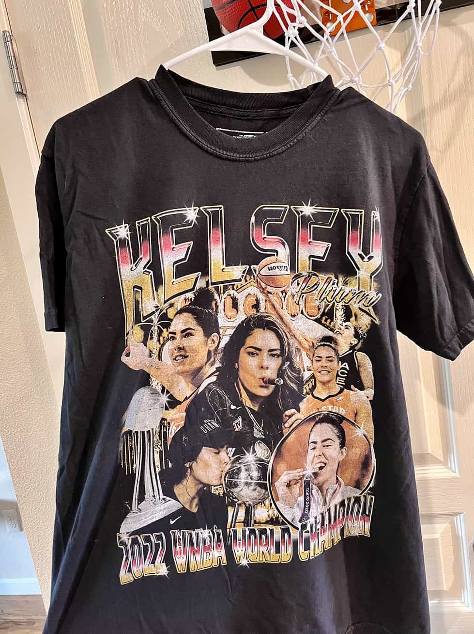 Front view of black Kelsey Plum 2022 WNBA Champion t-shirt featuring images of Plum celebrating the Las Vegas Aces’ victory.