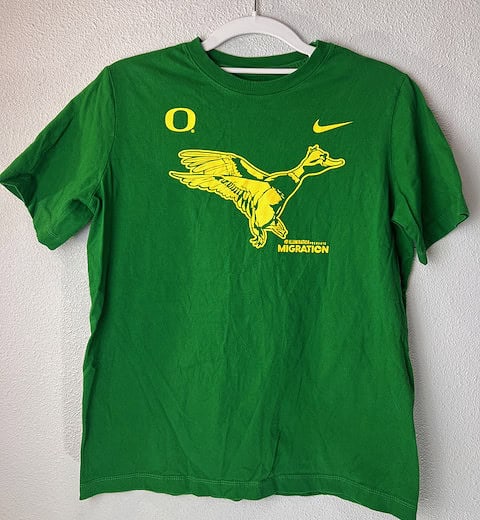 Front view of green Nike Oregon Ducks Migration collab T-shirt with yellow flying duck graphic and Oregon “O” logo.