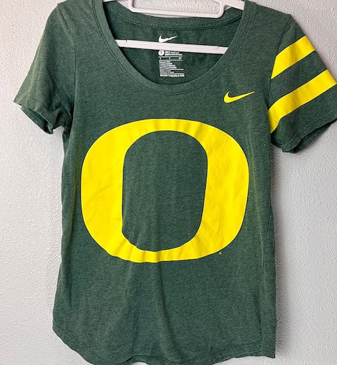 Front view of Nike Oregon Ducks green tee with yellow “O” logo and striped sleeves.