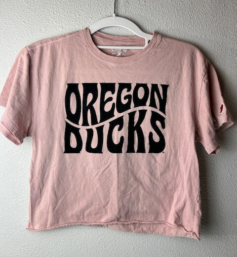 Front view of cropped pink Oregon Ducks tee with black retro logo and unfinished hem.