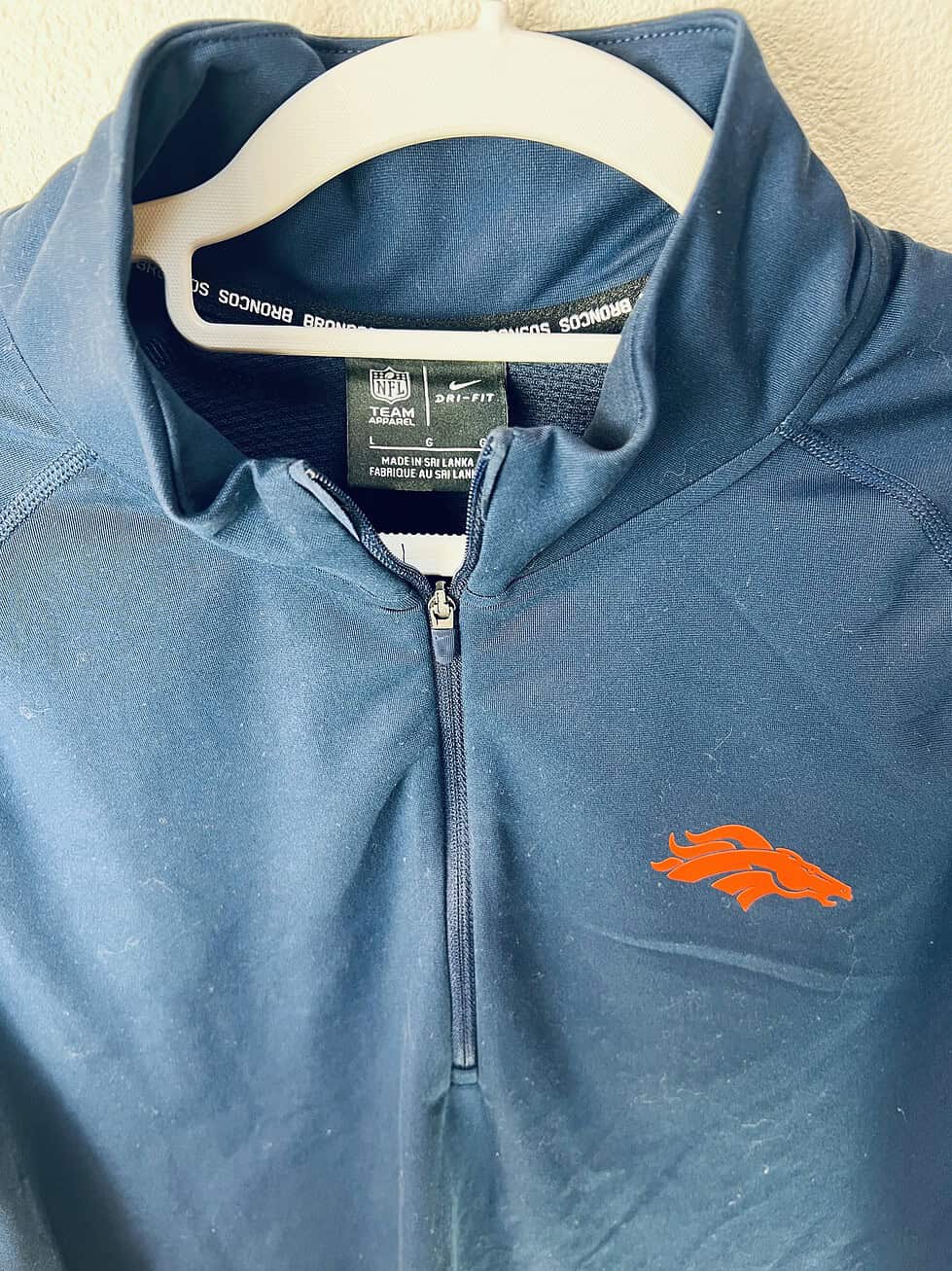 Close-up of embroidered Broncos logo and Nike NFL tag.