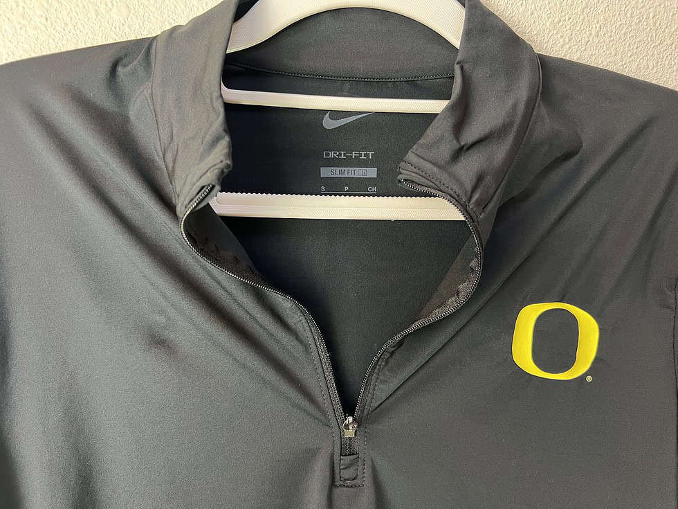 Close-up of Oregon "O" logo and Nike tag on black half zip long sleeve.