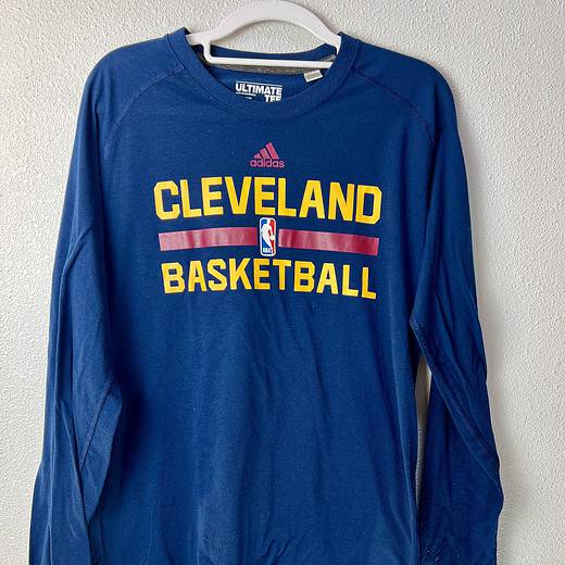 Front view of Adidas tee with words "Cleveland Basketball" printed in yellow on long-sleeve navy blue tee
