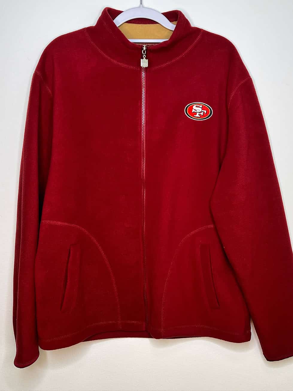 Front of red fleece zip up sweatshirt. Small logo on the upper right