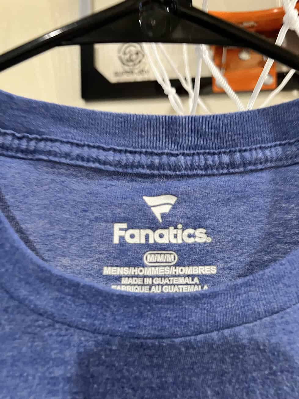 Close-up of the Fanatics logo and size label (Medium) inside a heathered blue T-shirt.