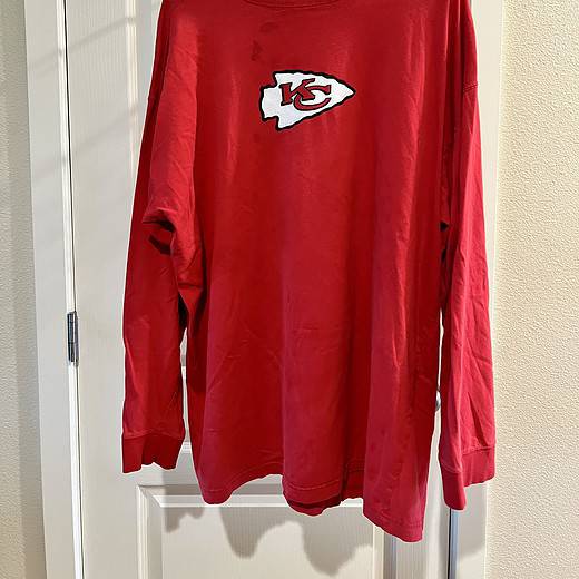 Front view of a red long-sleeve shirt with Kansas City Chiefs logo, showing minor marks near the collar.