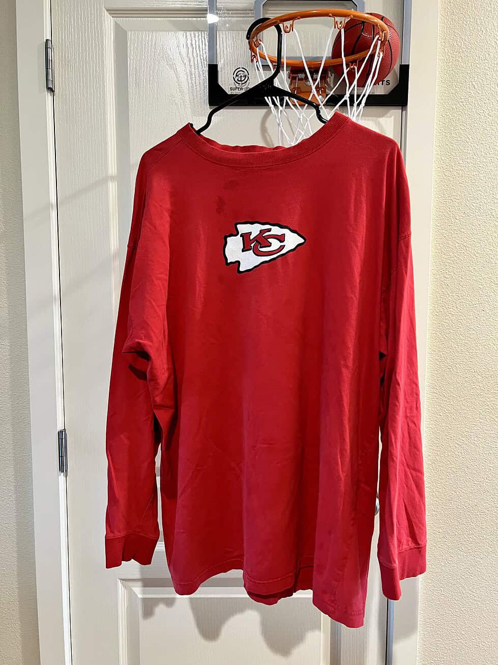 Front view of a red long-sleeve shirt with Kansas City Chiefs logo, showing minor marks near the collar.